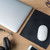 laser black mouse pad on wooden desk with laptop headphones glasses and white mouse