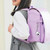 Laser white micro pocket camera clipped to purple school backpack