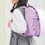 Laser pink micro pocket camera clipped to purple school backpack
