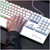 Hands typing on the white gaming keyboard beside its number pad