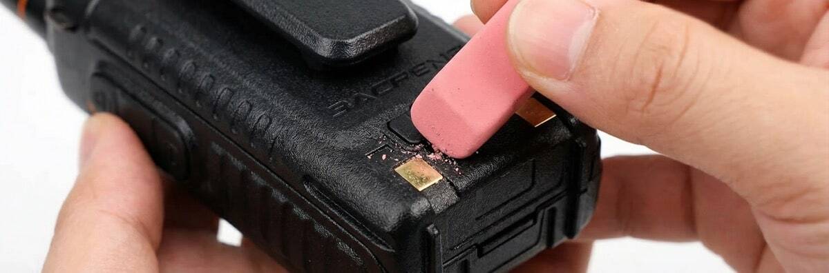 Using a pencil eraser to clean gold battery contacts on a two-way radio