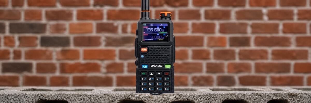 A handheld two-way radio placed on a concrete cinder block, representing indoor signal penetration and building obstacles.