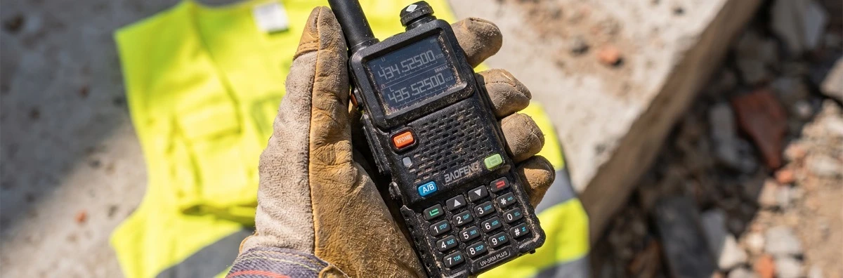 An industrial worker using a rugged Baofeng two-way radio on a busy construction site for instant and reliable group coordination.