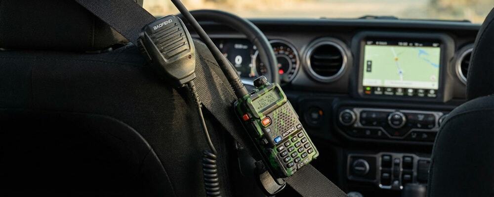 Walkie talkie speaker mic clipped to a seatbelt inside a 4x4 vehicle