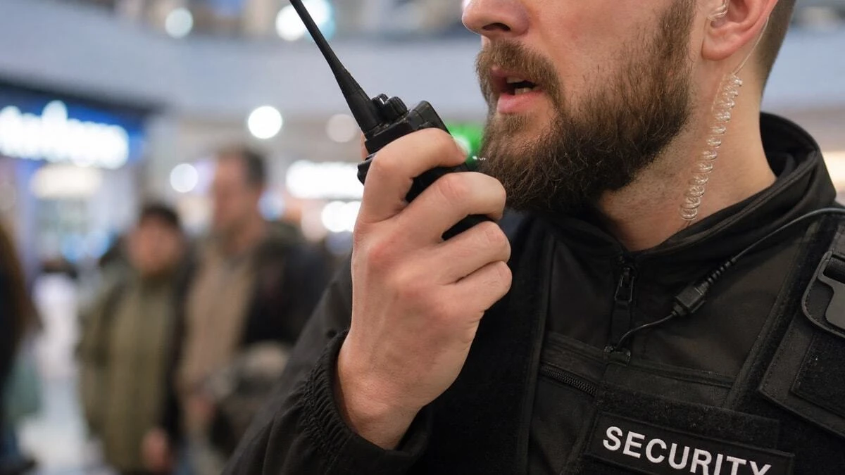 Security guard pressing push to talk button on a two way radio during an urgent situation