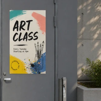 The poster features bold brushstroke graphics in teal, coral, yellow, and blue, along with small illustrations of paintbrushes in a jar. Sunlight casts soft shadows from nearby plants onto the concrete wall and greenery beside the door.