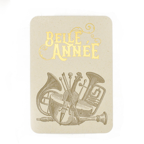 A greeting card with a sketch of a pile of orchestral instruments: a violin, timpani, French horn, and oboe. Above the sketch reads "Belle Année" in gold print.