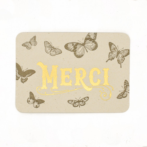 A greeting card covered in butterflies that reads "Merci" in gold print.
