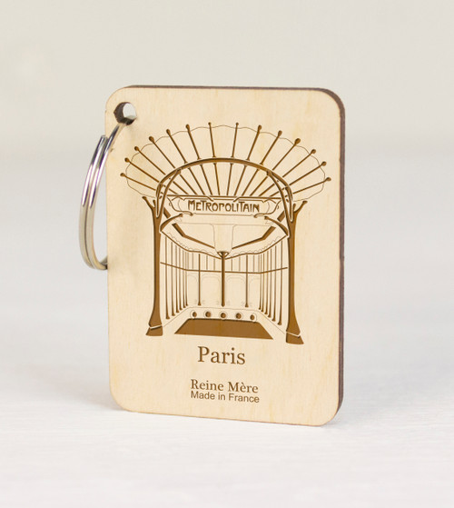 A key ring with a square wooden charm. The charm has an illustration of an ornate gate that serves as a Métro entrance.