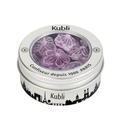 A 50 gram tin of Kubli candies shaped like violet flowers. The rim of the can is painted with the skyline of Paris.