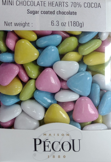 A 180 gram box of mini sugar-coated dark chocolate hearts from Pécou. The box has a clear window that showcases the yellow, blue, pink, and white hearts.