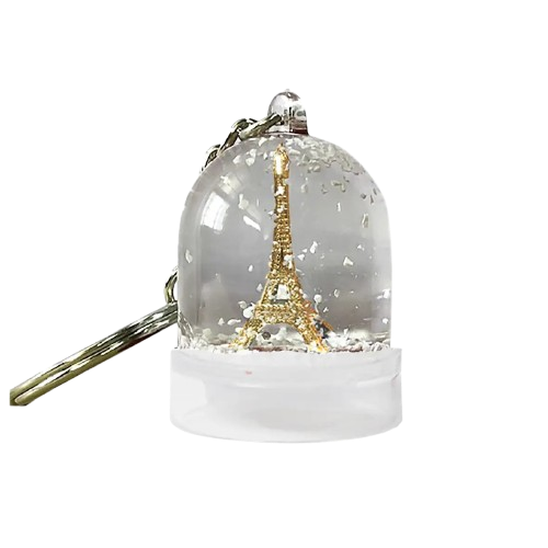 A key ring from Les Parisettes that comes with a mini snow globe attached. Inside the snow globe is a gold model of Eiffel Tower.