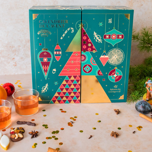 A square teal "duo" advent calendar with organic tea from Provence d'Antan. The calendar is in two clear segments and the front features an abstract Christmas tree with segments of various patterns. The calendar sits on a table.