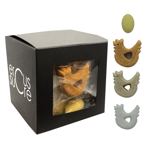 A black 95 gram box of individually wrapped Ercus hen and egg-shaped sugar pieces. Samples of the white, amber, and brown hens and the yellow eggs are displayed to the side of the box.