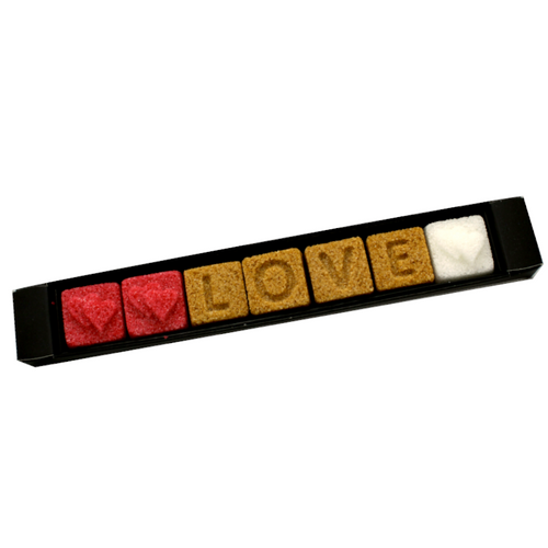 A 30 gram sleeve of Ercus "Love" sugar pieces. The seven red, brown, and white square pieces each have a single character on them, spelling out the word "love" padded with hearts.