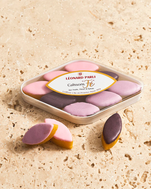 A diamond-shaped box of 55 grams of mini floral calissons from Léonard Parli displayed on a stone countertop.