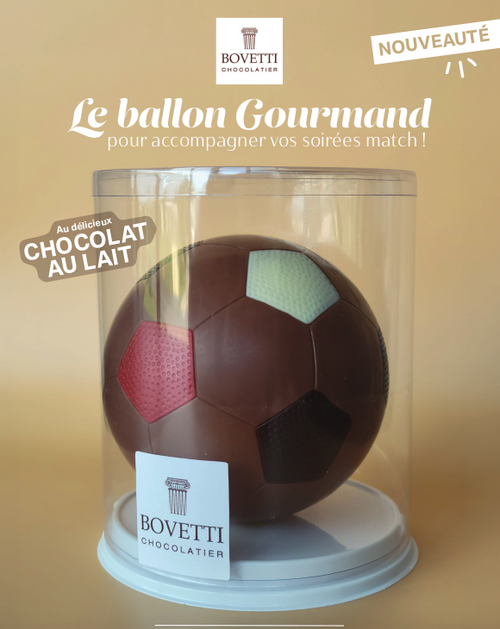 A 150 gram hollow milk chocolate soccer ball, with multi-colored paneling, displayed in a round clear case. Bovetti's logo is featured on and above the case, with text below that says "Le balloon Gourmand pour accompagner vos soirées match!"