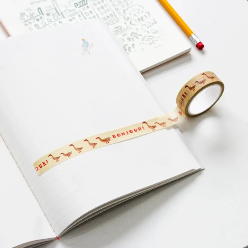 A masking tape that reads "Bonjour!" with a goose drawing displayed on a notebook page.