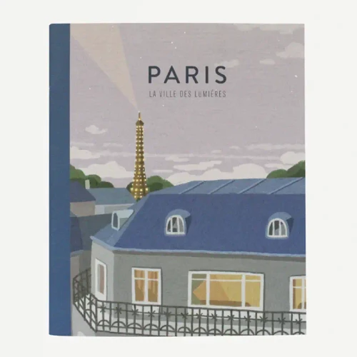A notebook with a cover illustration showing a view of Paris in the evening. The top of a building is in the foreground and the illuminated Eiffel Tower is in the background. The notebook is titled "Paris La ville des lumières."