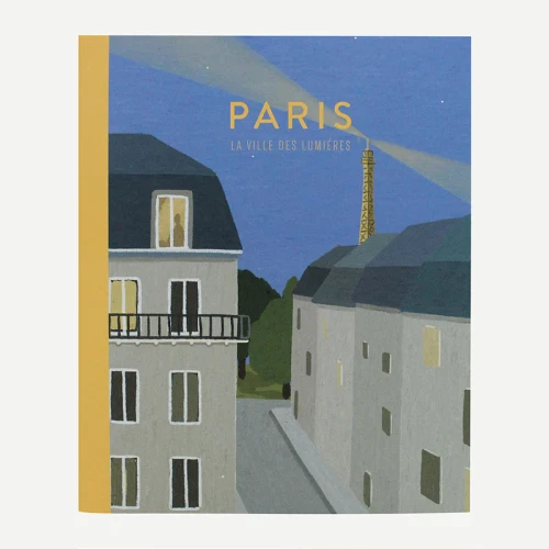 A notebook with a cover illustration showing a view of Paris by night. Buildings are in the foreground and the Eiffel Tower is in the background. The notebook is titled "Paris La ville des lumières."