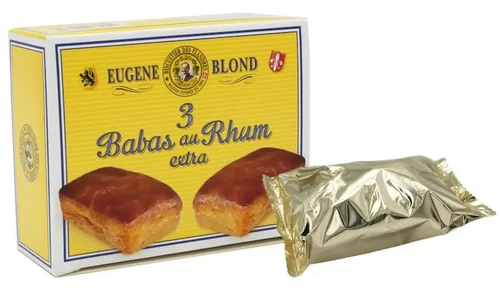 A yellow box containing three babas au rhum in individual pouches. One pouch is sitting in front of the box.