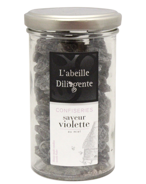 A 130 gram jar of violet honey candy from L'Abeille Diligente. The purple candies are shaped like flowers.