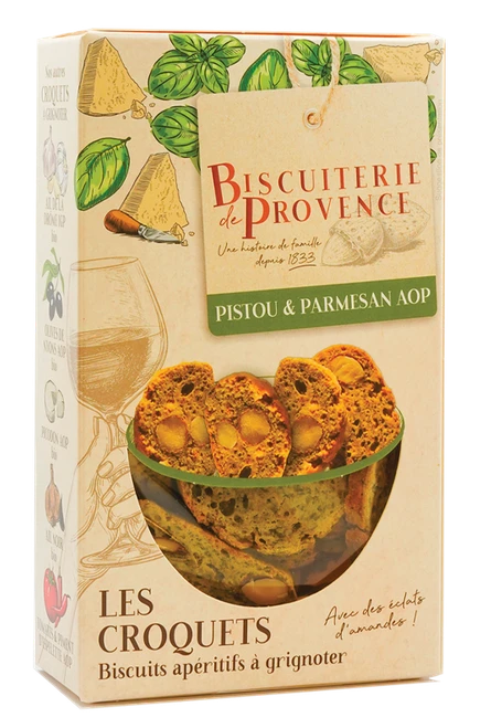 A 90 gram box of organic croquets with pistou and Parmesan from Biscuiterie de Provence. The crisp, green crackers with almond pieces are visible through the box's window.