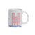 A mug from Les Parisettes featuring an abstract drawing of Notre-Dame made out of horizontal red lines. The ground is represented by blue lines and clouds are scattered throughout the sky.