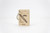 A key ring with a square wooden charm. The charm has an illustration of a baguette, béret, and mustache.