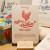A "Poule" card from L'Atelier Letterpress's "Excuse My French" series, displayed on a stand on a table. A sketch of a chicken is at the top of the card. Below it in sweep cursive text reads, "Roll my chicken! Roule ma poule!" It is accompanied with an explanatory paragraph: "'Roule ma poule!' is an informal French expression which means "Let's go!" or "Let's do this!" and expresses enthusiasm. Its popularity comes from the pleasant sound of the rhyme.