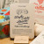 A "Fromage" card from L'Atelier Letterpress's "Excuse My French" series, displayed on a stand on a table. A sketch of cheese wheel is at the top of the card. Below it in sweep cursive text reads, "To make a whole cheese. En faire tout un fromage." It is accompanied with an explanatory paragraph: "'En faire tout un fromage' is a familiar French expression which means to exaggerate an event or a situation. The idea is to start from something quite simple like milk and up with something very sophisticated like cheese. This can be translated as, "to make a meal of it."