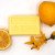 A 100 gram yellow bar of lemon and donkey milk soap from Senteurs de France. The bar is surrounded by lemon wedges.