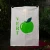 The Reine Mère "Apple" tea towel hanging from a clothes line. You can see a green apple on a white towel with a grid pattern. Beside the apple the towel says "Vert" in bold green font.