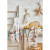 The "Christmas Forest" apron from Coucke laid across a kitchen countertop. The white apron with green-gray straps depicts a snowy village overhung by a gondola lift.