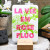 A card from L'Atelier Letterpress that reads, "La vie en rose fluo" in pink lettering in front of an illustration of a green rose. The card sits on a display stand.