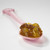 Muroise & Co Christmas jam with apple, pear, and walnut on a pink spoon. The ocher jam is fruit-heavy, with chunks of preserved fruit still visible.