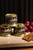 Three cans of Les Canardises duck foie gras stacked on a table next to grapes and crackers. The flavors of foie gras displayed are Champagne, Port wine, and plain.