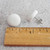 A close-up image of two white fabric button earrings next to a ruler. The fabric buttons are about half an inch wide with a half inch long butterfly back.