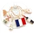 Six wine charms held on a glass hook by their key rings. The designs of the charms are of the French flag, the Moulin Rouge, the Eiffel tower, a wine bottle, a perfume bottle, and a croissant.