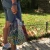 Lower half of a person in shorts, outside, holding a cotton mesh shopping bag colored like the French flag.