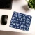A navy blue computer mouse pad illustrated with with drawings of Paris monuments next to a computer keyboard and mouse.