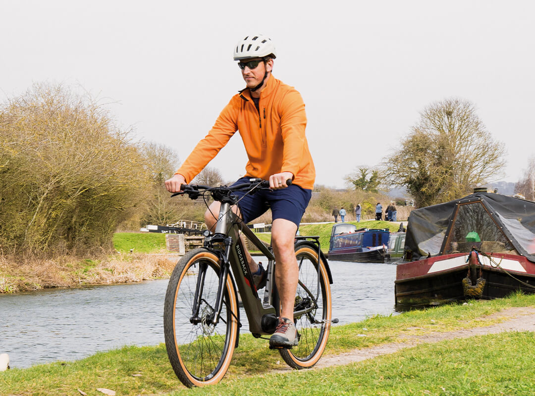 Man cycling on an e-bike, alongside a canal