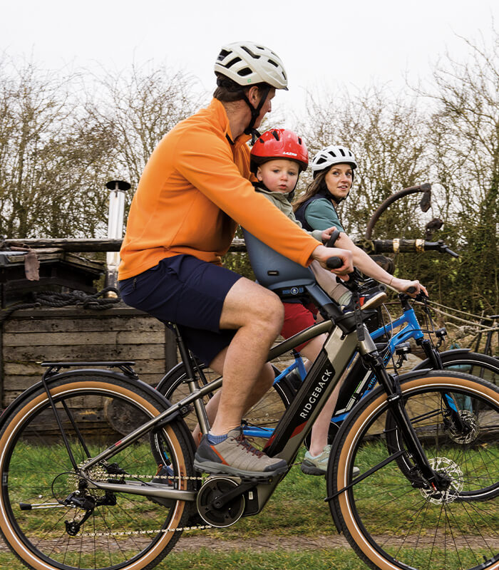 A man, woman and baby cycling on e-bikes