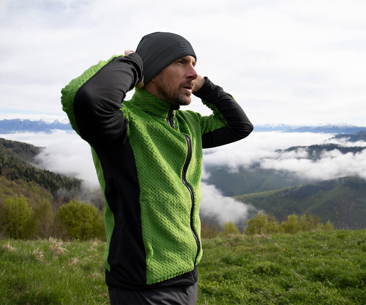 Man stood on top of mountain, above the clouds, wearing new Alpine Green Komondor Fleece.