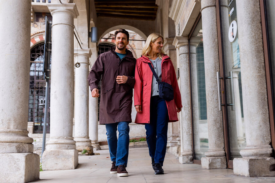 Man and WOman Wearing Lightweight Kendal Waterproof Jackets Walking Through a City