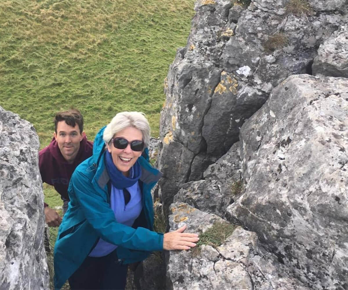 Liz and man climbing a rock in Derbyshire.