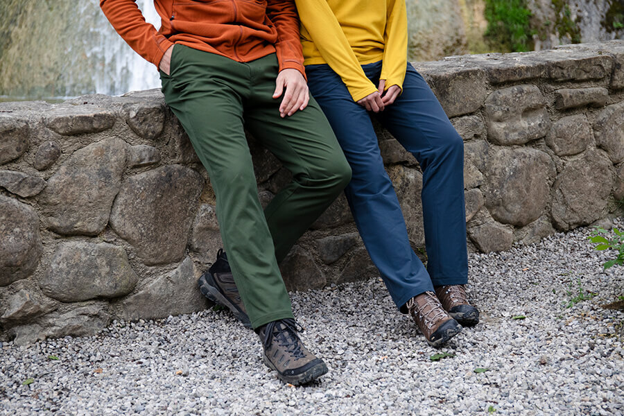 Man and woman leaving against a brick wall, btoh wearing Oboz walking boots