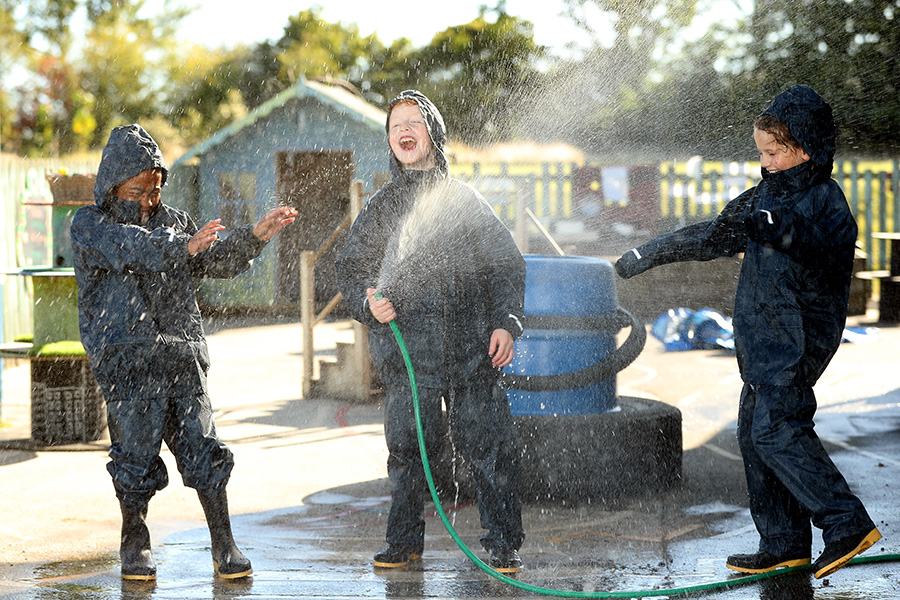 The Outdoor Guide Foundation children in waterproof clothing and wellies playing with a water hose pipe