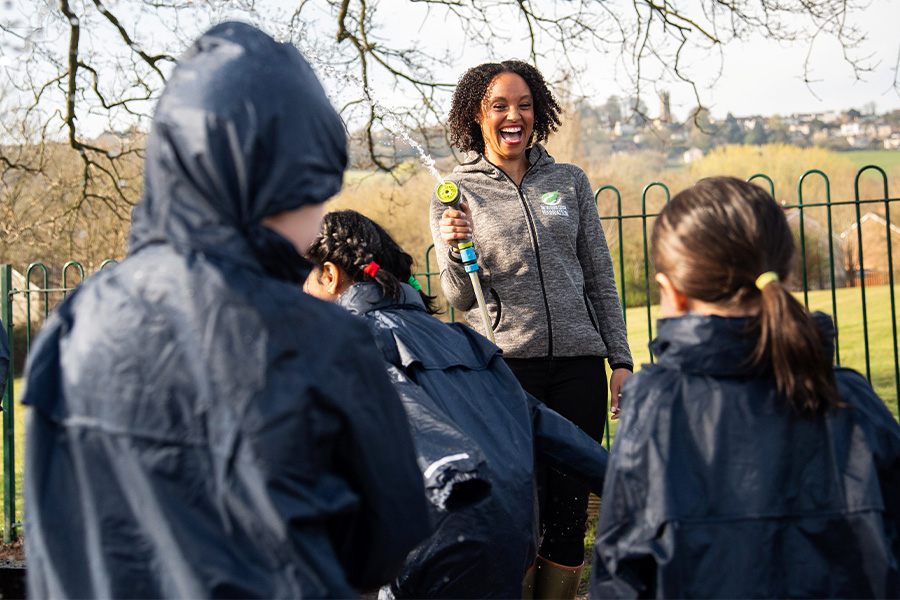 The Outdoor Guide Foundation  children in waterproof clothing with an adult spraying a hosepipe on them