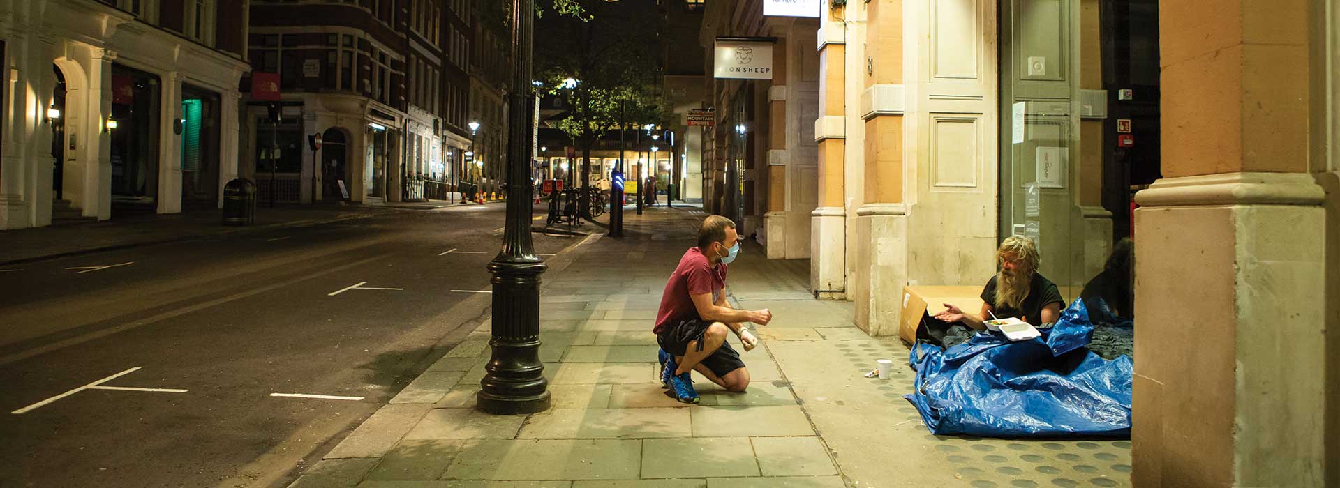 Man talking to homeless person on a street